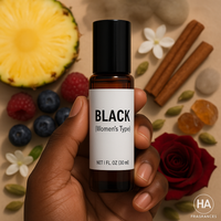 A bottle of Black (Women’s Type) Body Oil held by a dark-skinned hand, surrounded by cinnamon sticks, jasmine and rose petals, sandalwood pieces, and amber stones, with the HA Fragrances logo in the corner.