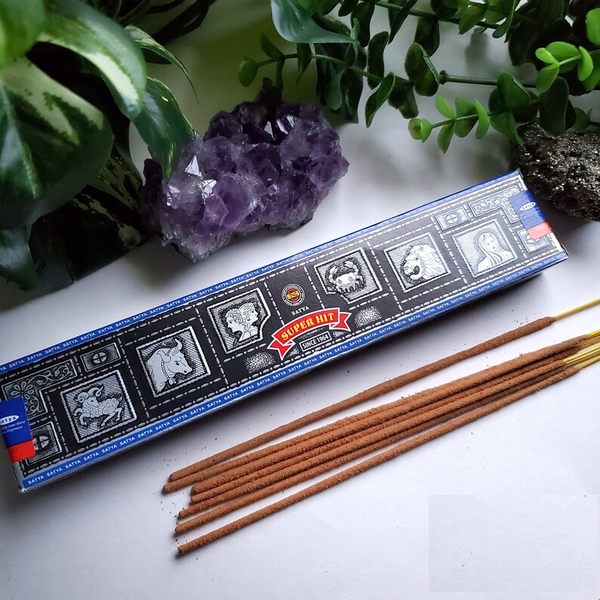 Satya Super Hit Incense 15g pack with hand-rolled incense sticks, displayed alongside natural greenery and a purple amethyst crystal, highlighting its luxurious and calming aroma.